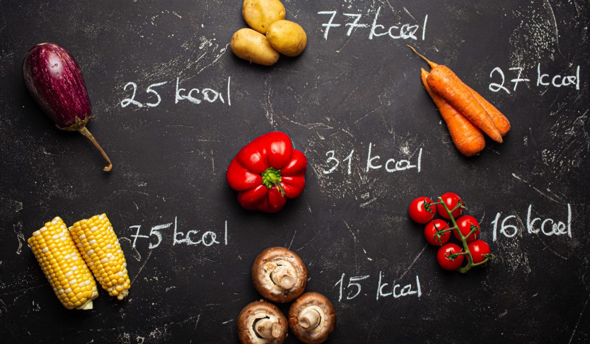 Top view of different vegetables on black stone background and chalk