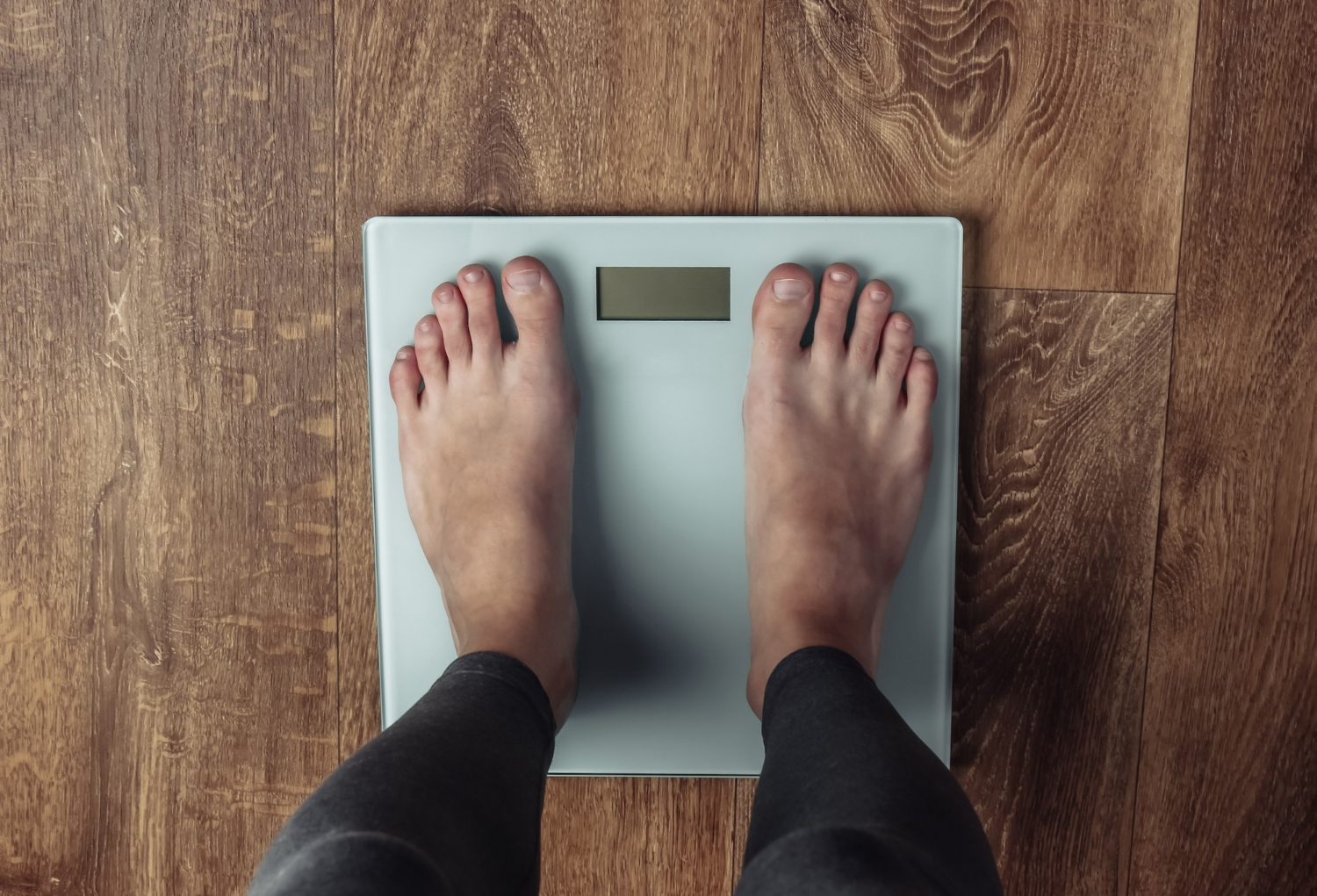 scale image Woman with bare feet is weighed on the scales on the floor