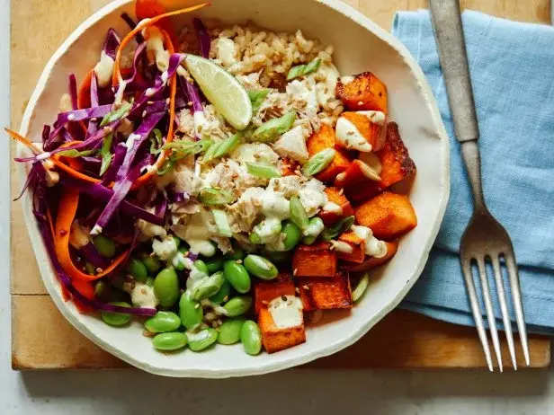 Colorful bowl with brown rice, roasted sweet potatoes, tofu, edamame and fresh vegetables