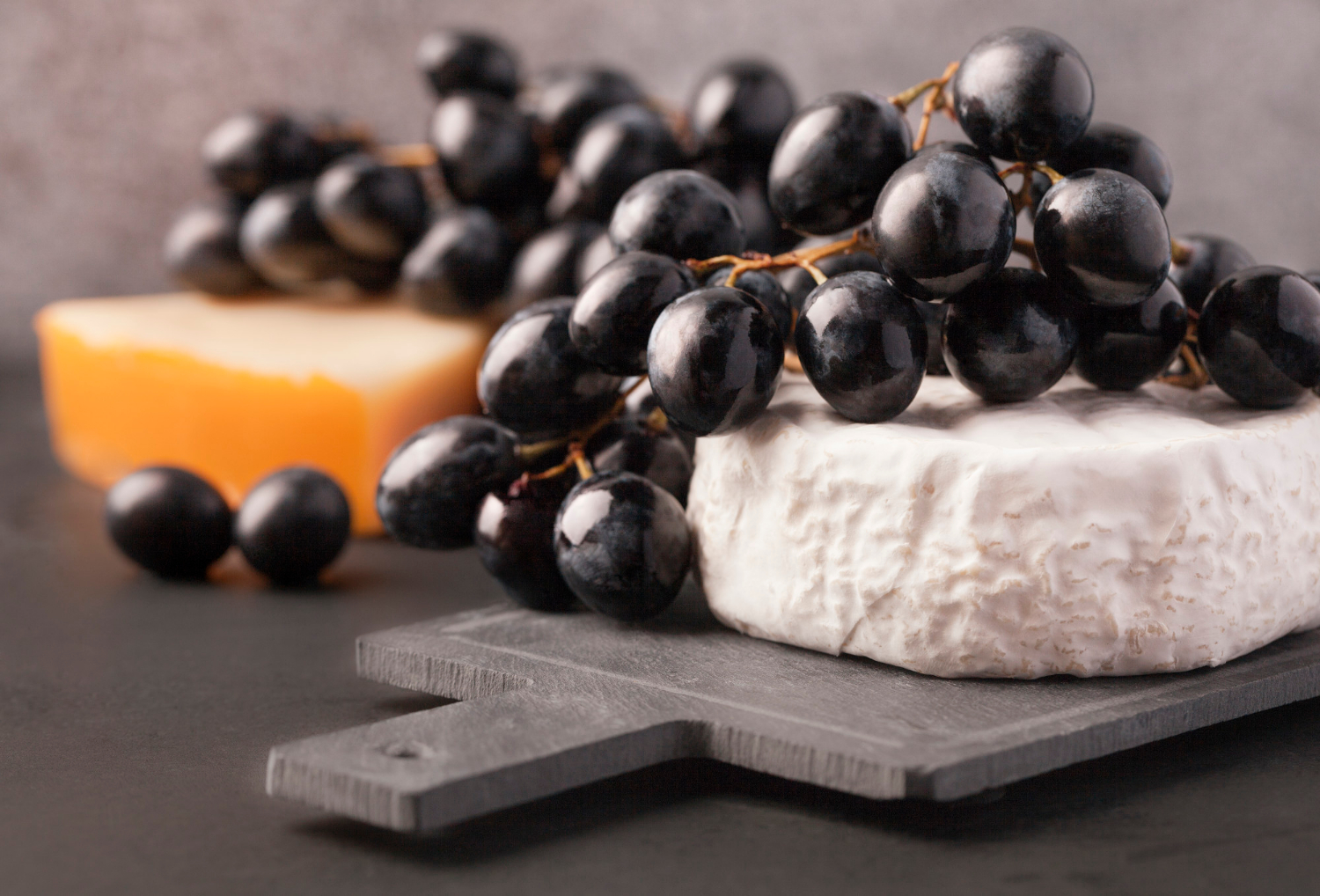 grapes-and-blocks-of-cheese Black grapes with soft french cheese on the board as an appetizer for wine