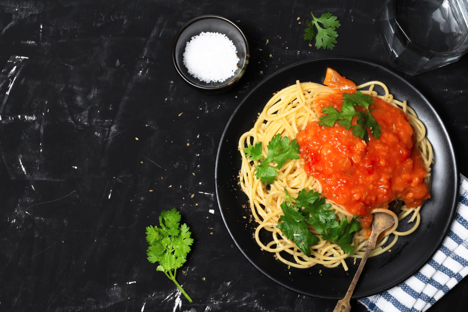 spaghetti Pasta with tomato sauce in black dish on black wood background