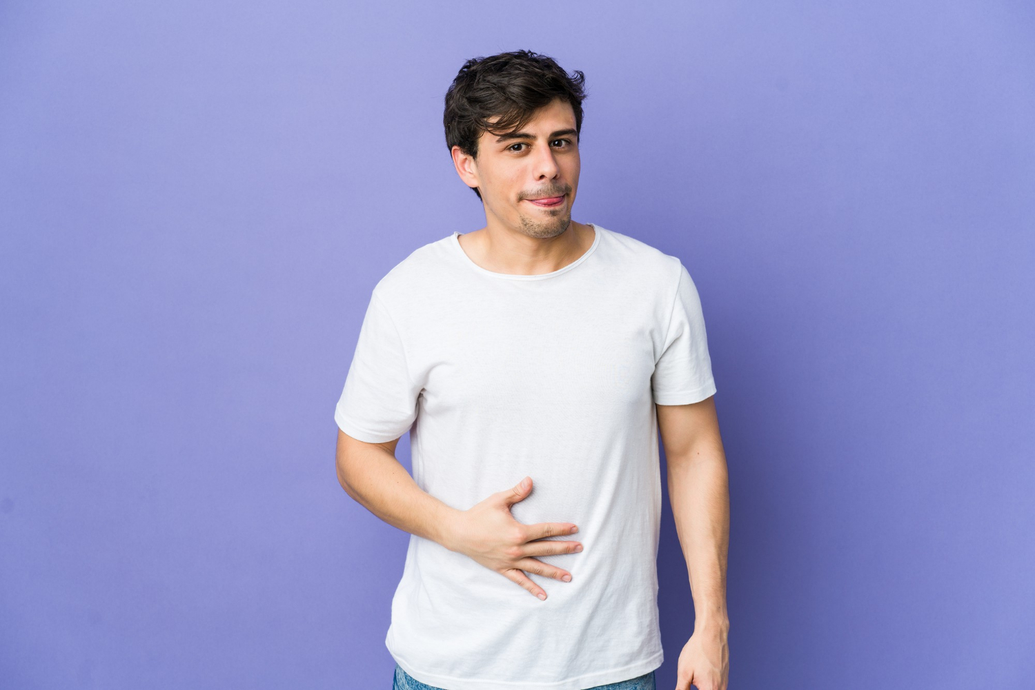 shutterstock_796941430 Young cool man touches tummy, smiles gently